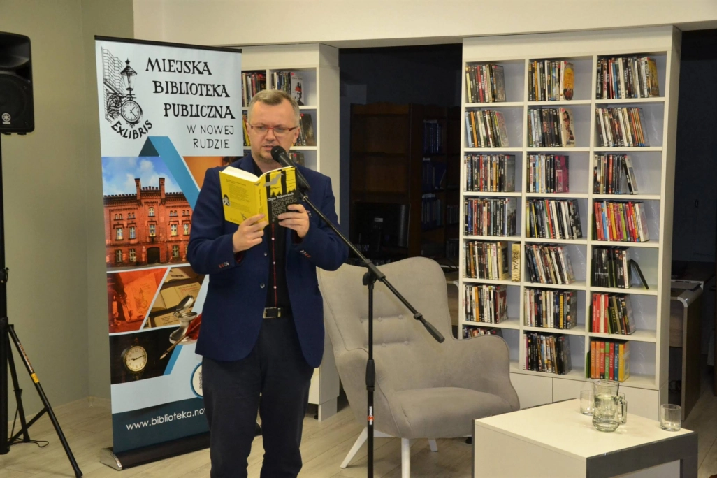 Dyrektor MBP Sławomir Drogoś czytający książkę Olgi Tokarczuk w Czytelni - powiększenie
