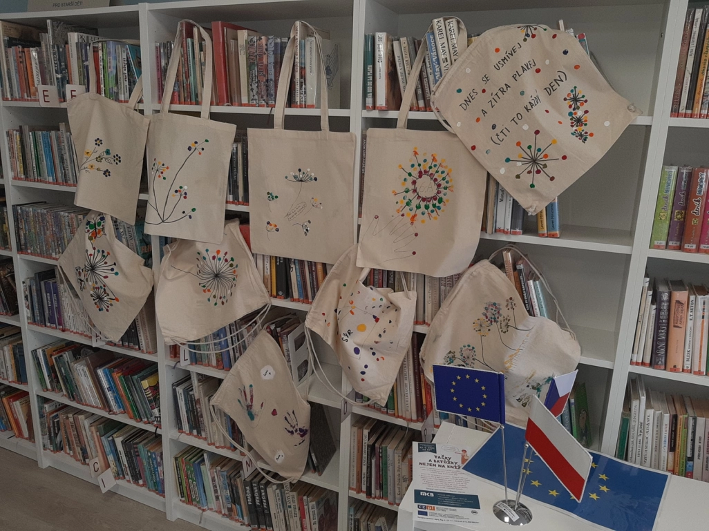 Płocienne torby pomalowane przez uczestników warsztatów - prezentacja na regale bibliotecznym - powiększenie
