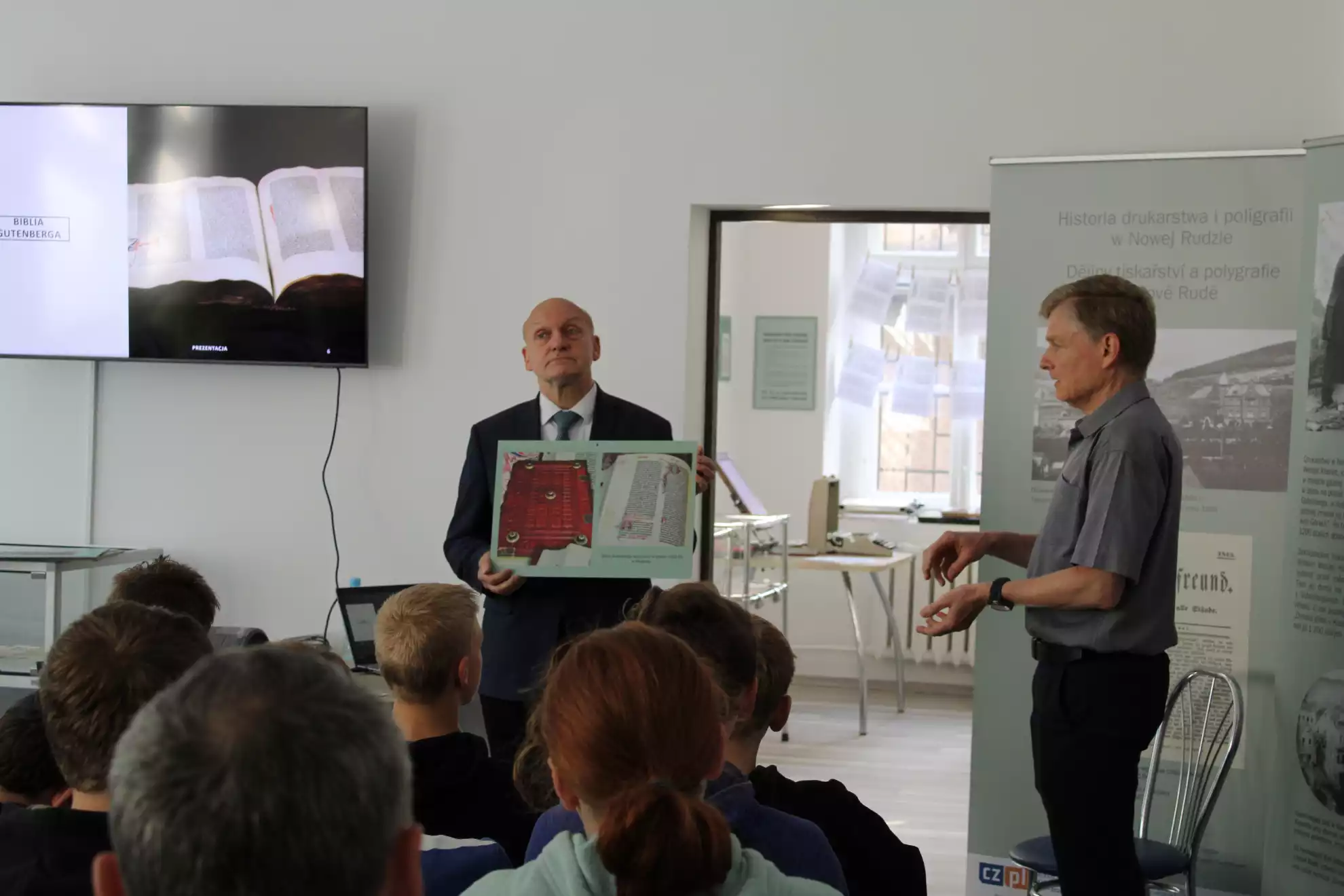 Julian Golak pokazuje uczniom tablicę z biblią Gutenberga. Petr Neuman tłumaczy na język czeski. - powiększenie