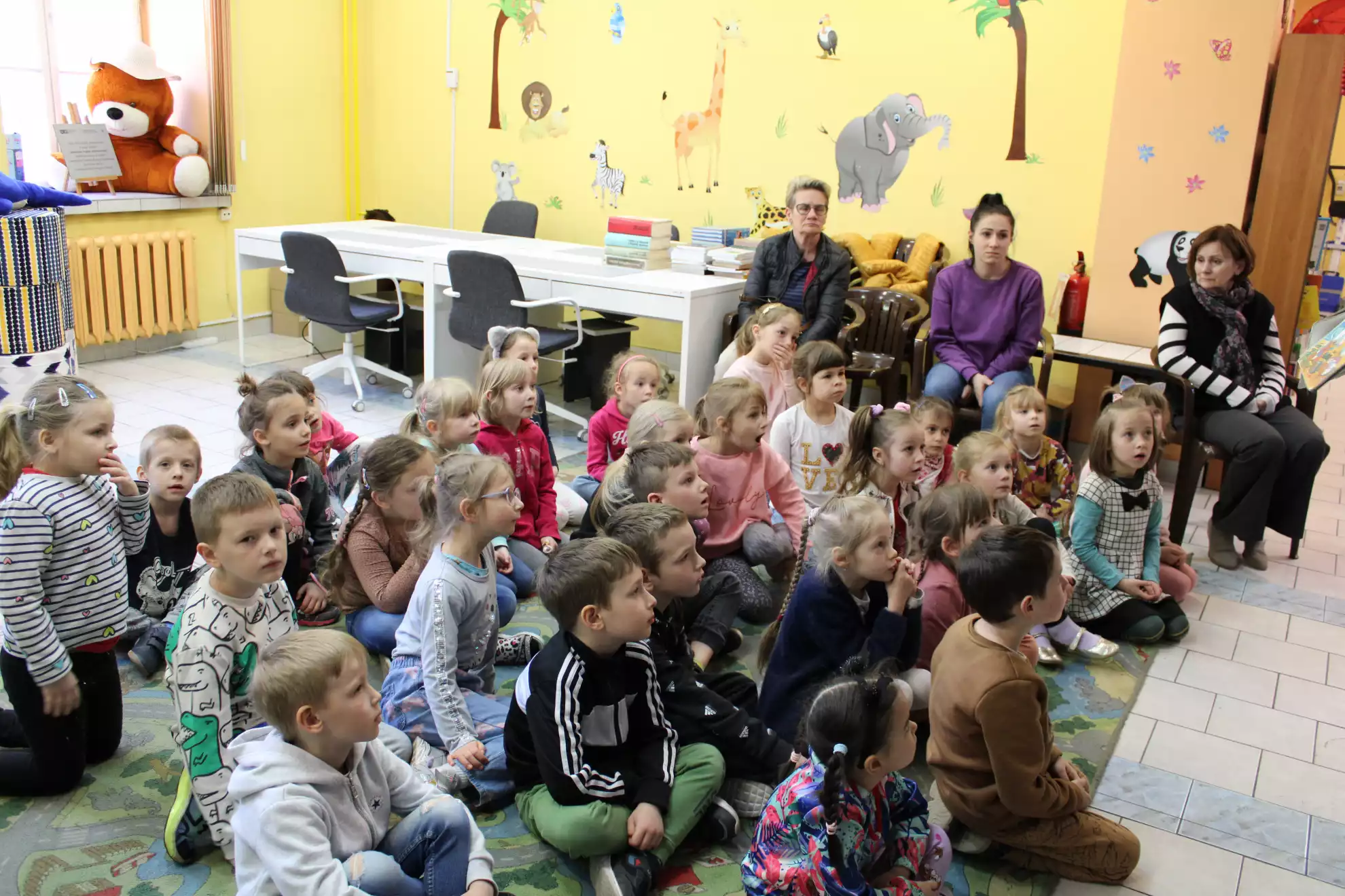 Grupa dzieci słucha prowadzącej zajęcia - powiększenie