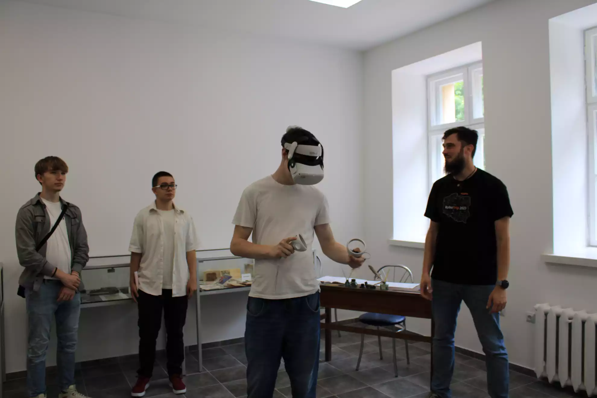 Uczestnik festiwalu w obecności dwóch kolegów i przedstawiciela WSSE zapoznaje się z technologią VR - powiększenie