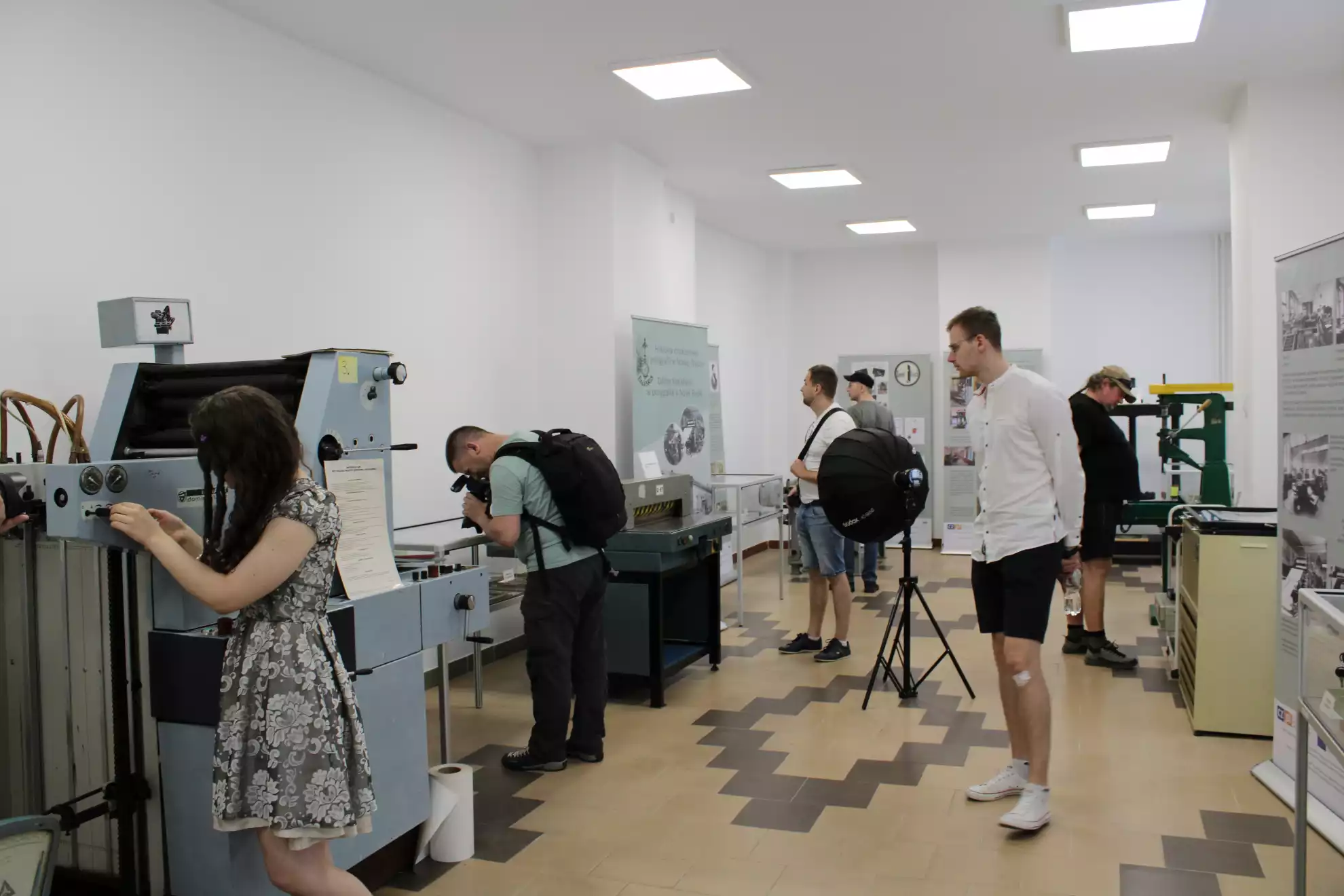 Uczestnicy fotospaceru zapoznają się ze sprzętem drukarskim w Sali Poligraficznej MBP. - powiększenie