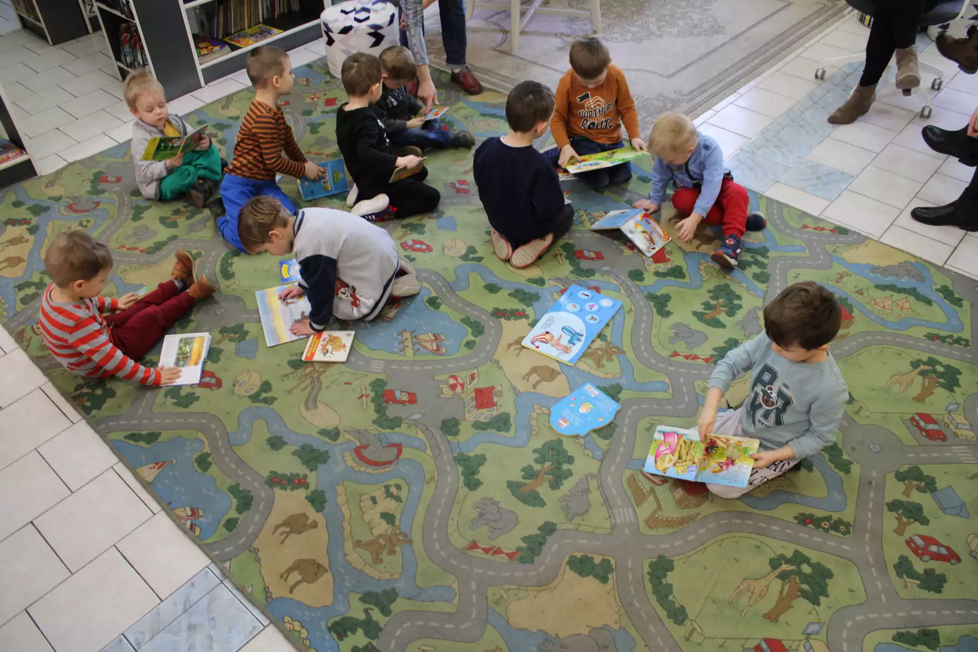 Dzieci siedzą na dywanie i oglądają książeczki.  - powiększenie