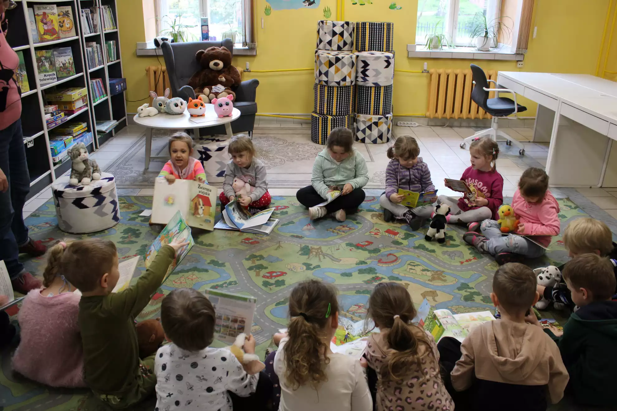 Dzieci siedzą na dywanie i oglądają książki.  - powiększenie