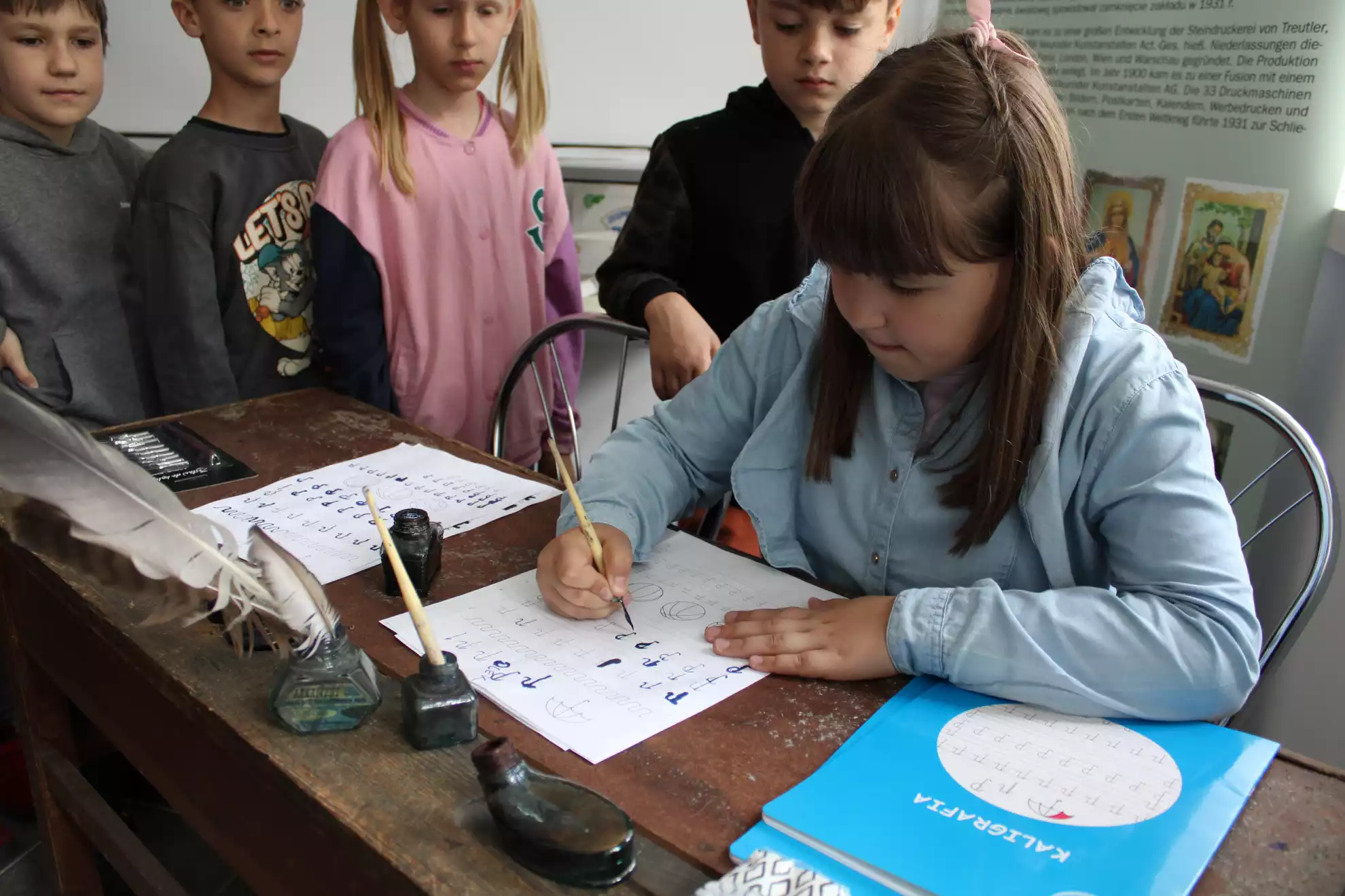 Dzieci piszą piórem przy starym biurku szkolnym.  - powiększenie