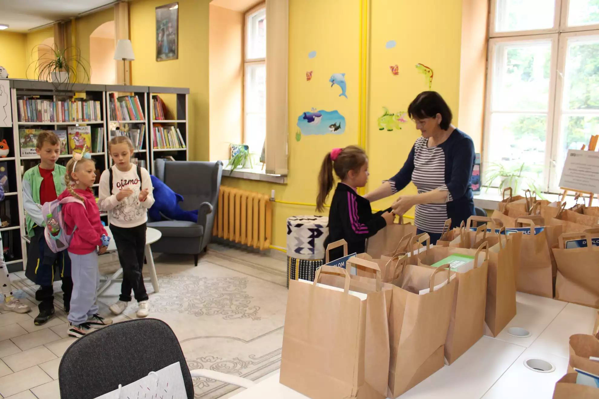 Bibliotekarka Oddziału dla Dzieci wręcza nagrodę uczestnikowi konkursu - powiększenie