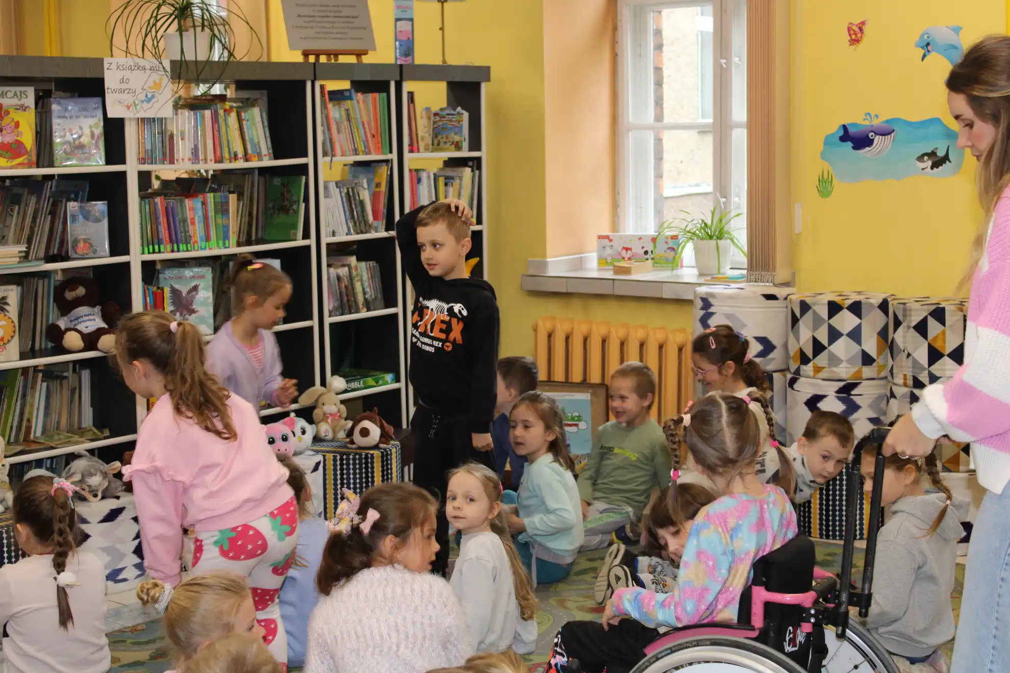 Dzieci siedzą na dywanie i oglądają książeczki.  - powiększenie
