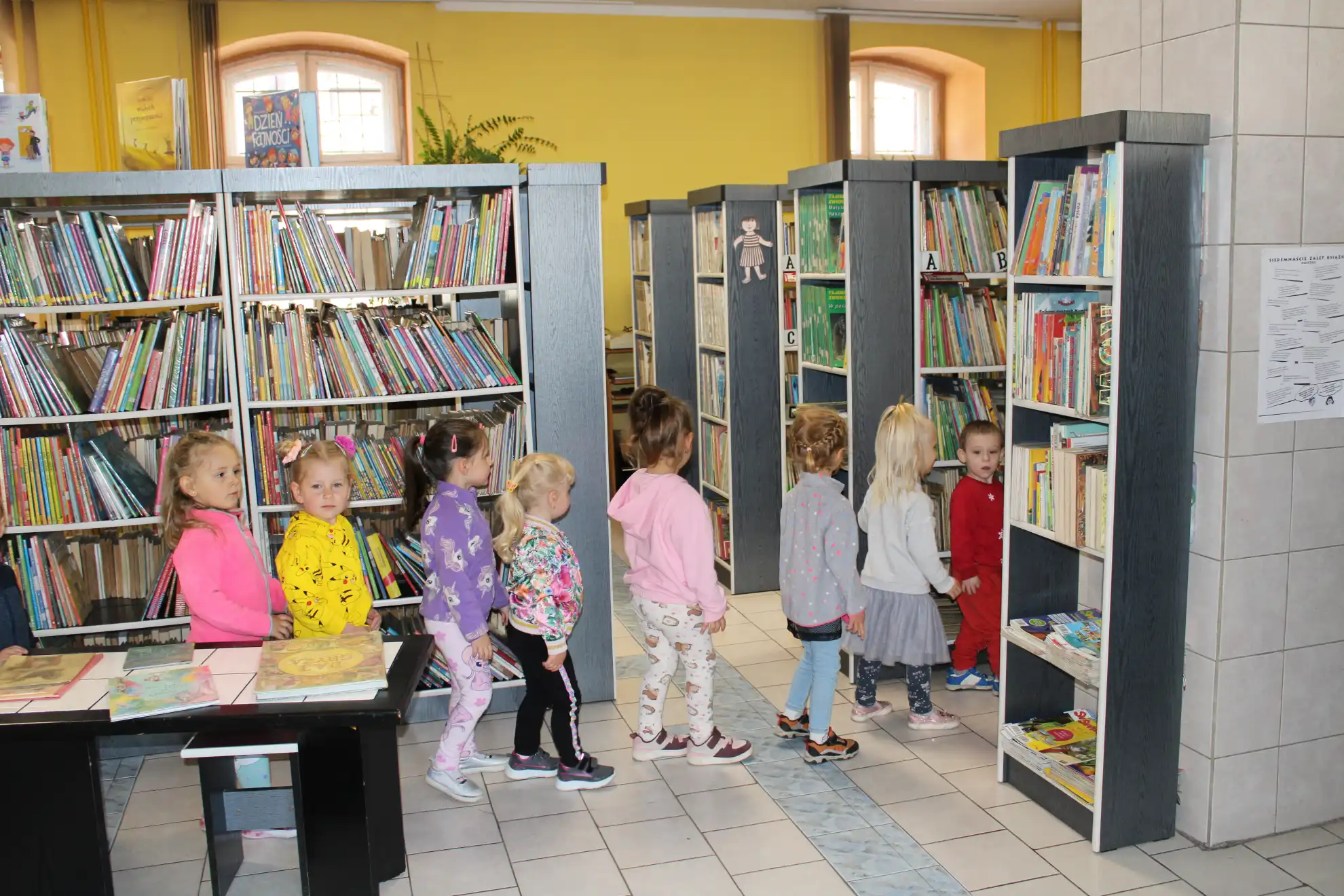Dzieci spacerują między regałami.  - powiększenie