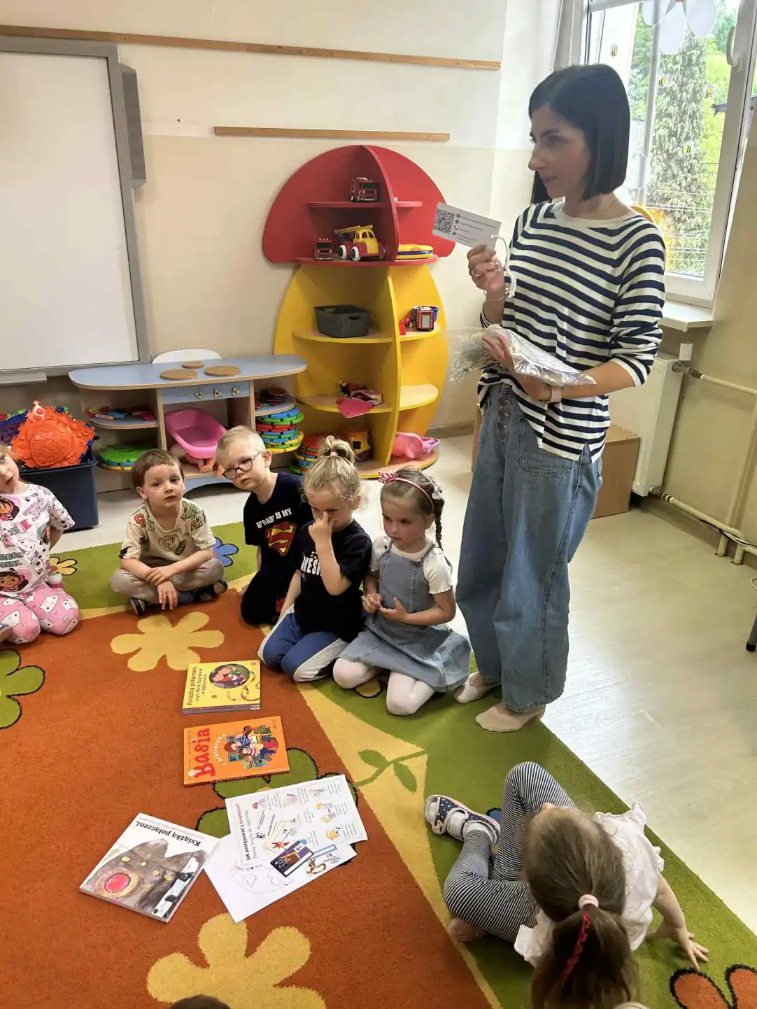 Pani bibliotekarka rozdaje dzieciom zakładki do książek, do samodzielnego pokolorowania.  - powiększenie