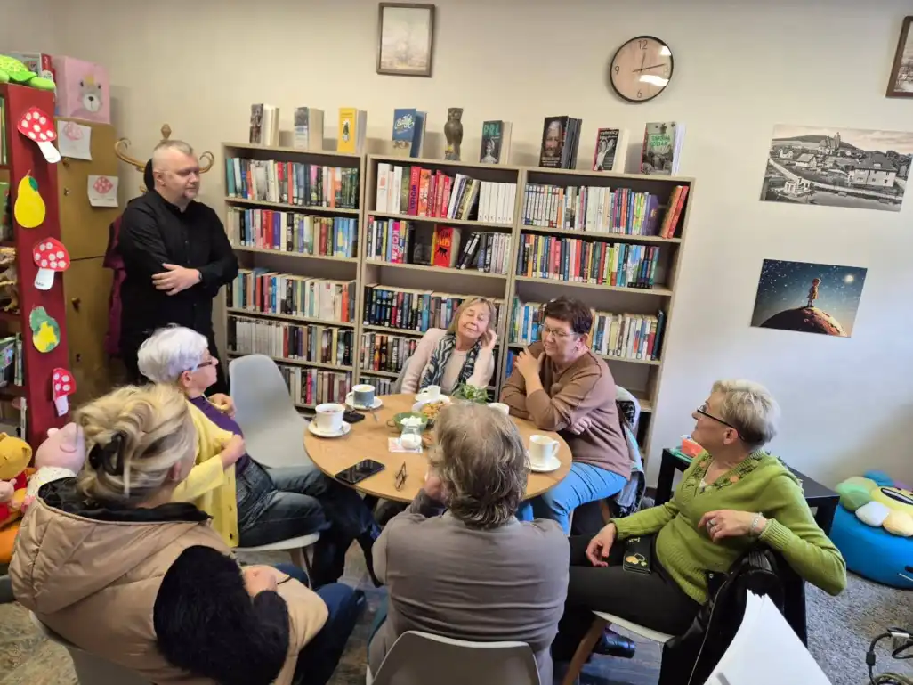 Dyrektor stoi przy stole, przed którym siedzą czytelniczki Filii Nr 1 - powiększenie