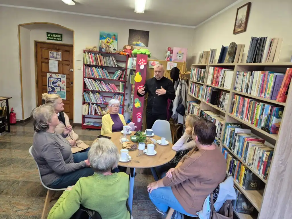 Dyrektor MBP w trakcie rozmowy z czytelniczkami Filii Nr 1, siedzącymi przy stole. - powiększenie