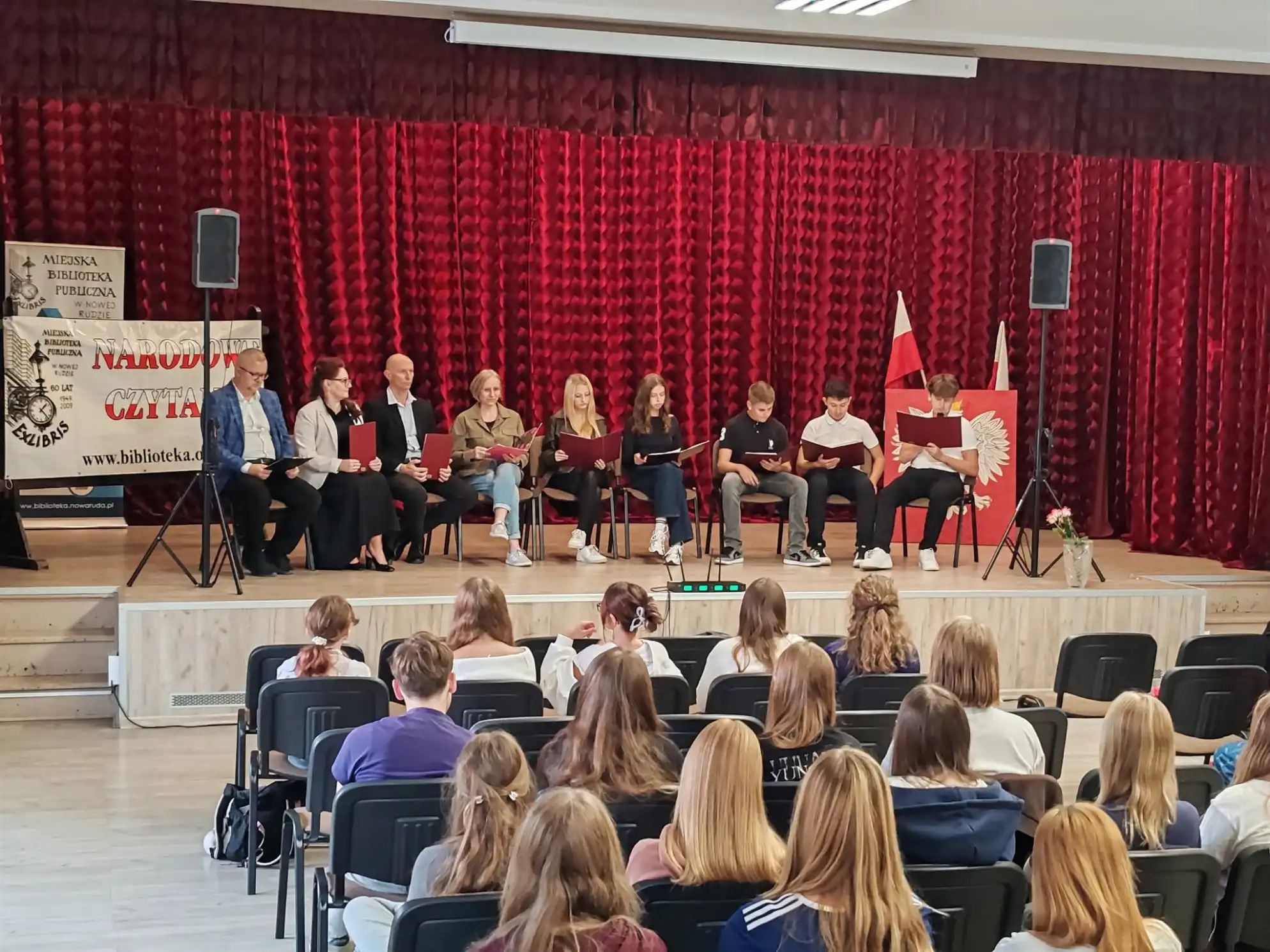 Uczestnicy Narodowego Czytania siedzą na scenie czytając fragmenty Dziadów Adama Mickiewicza. - powiększenie