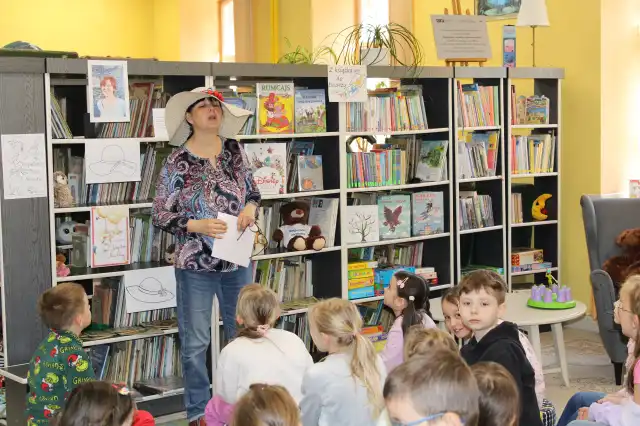 Pani bibliotekarka opowiada dzieciom o lekturze. 