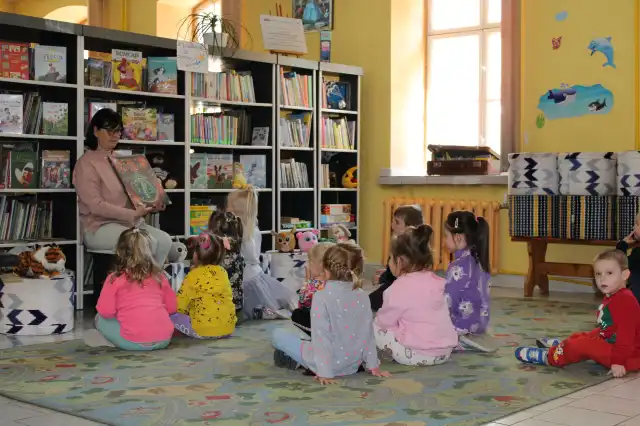 Pani bibliotekarka pokazuje dzieciom książeczki. 