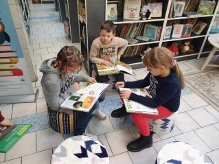 Trójka uczniów przegląda książki w Oddziale dla Dzieci