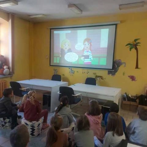 Dzieci oglądają prezentację multimedialną wyświetlają na ekranie naściennym