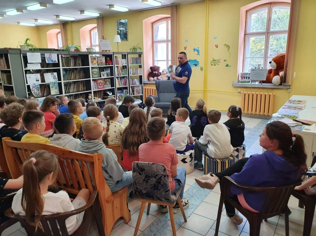 Norbert Kościesza stoi przed zgromadzonymi uczniami w Oddziale dla Dzieci