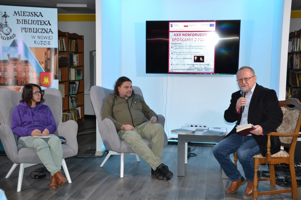 Karol Maliszewski i dwójka tegorocznych laureatów siedzą przed publicznością
