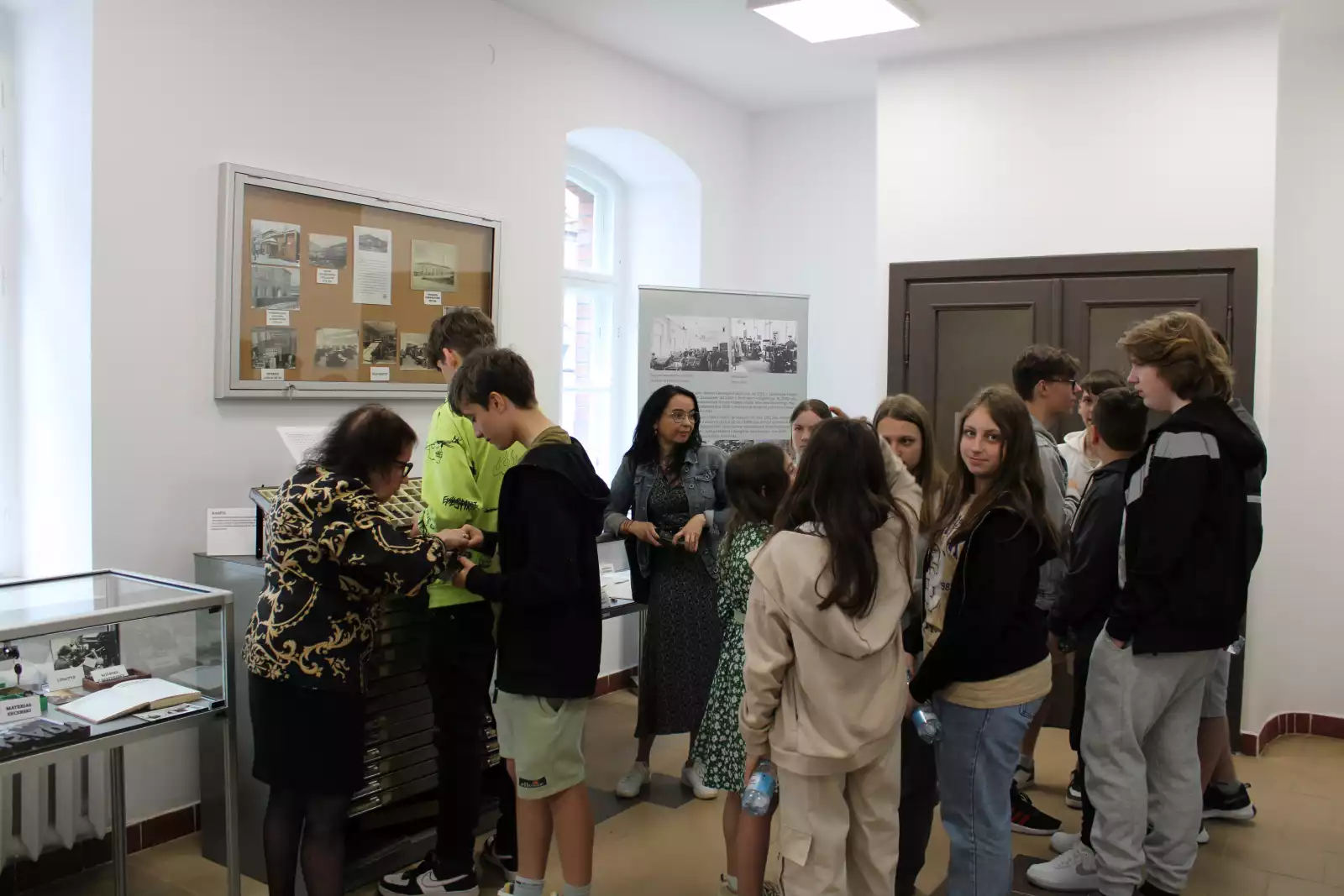 Uczniowie wraz z nauczycielami i prowadzącymi oglądają eksponaty muzealne.
