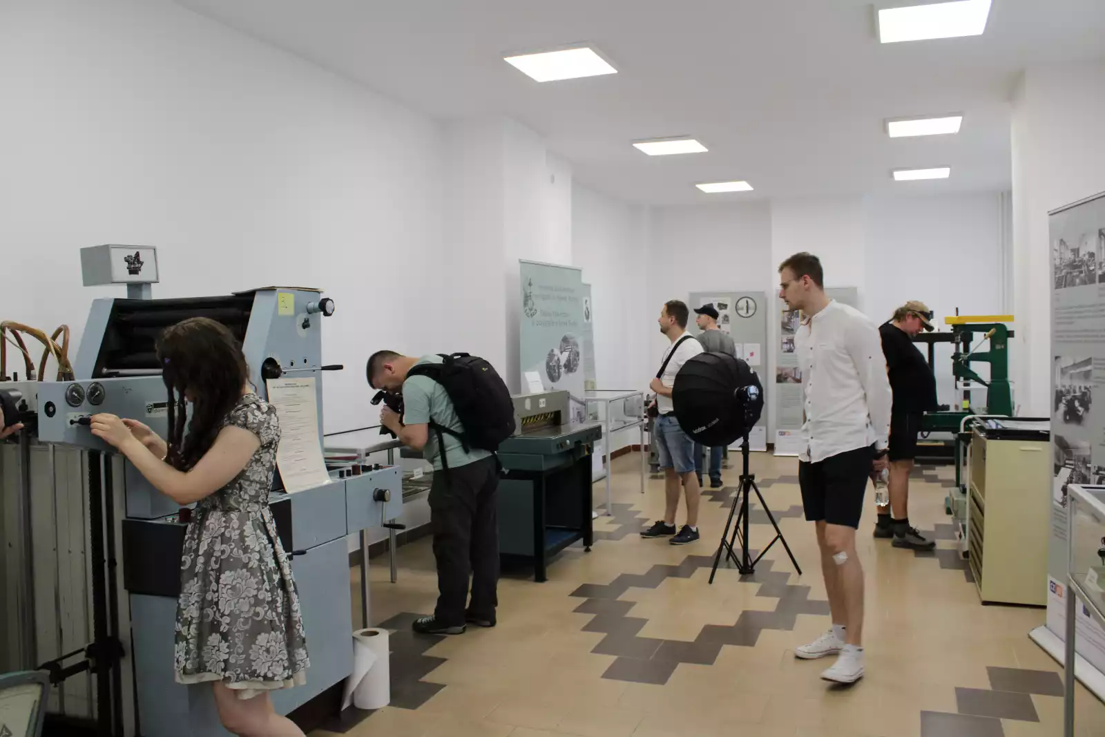 Uczestnicy fotospaceru zapoznają się ze sprzętem drukarskim w Sali Poligraficznej MBP.
