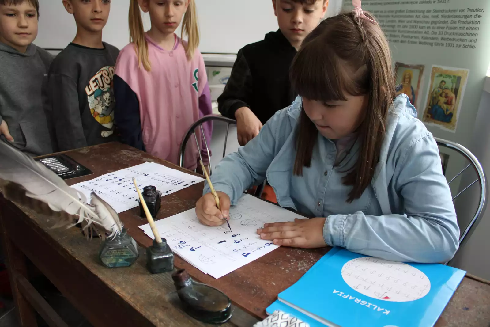 Dzieci piszą piórem przy starym biurku szkolnym. 