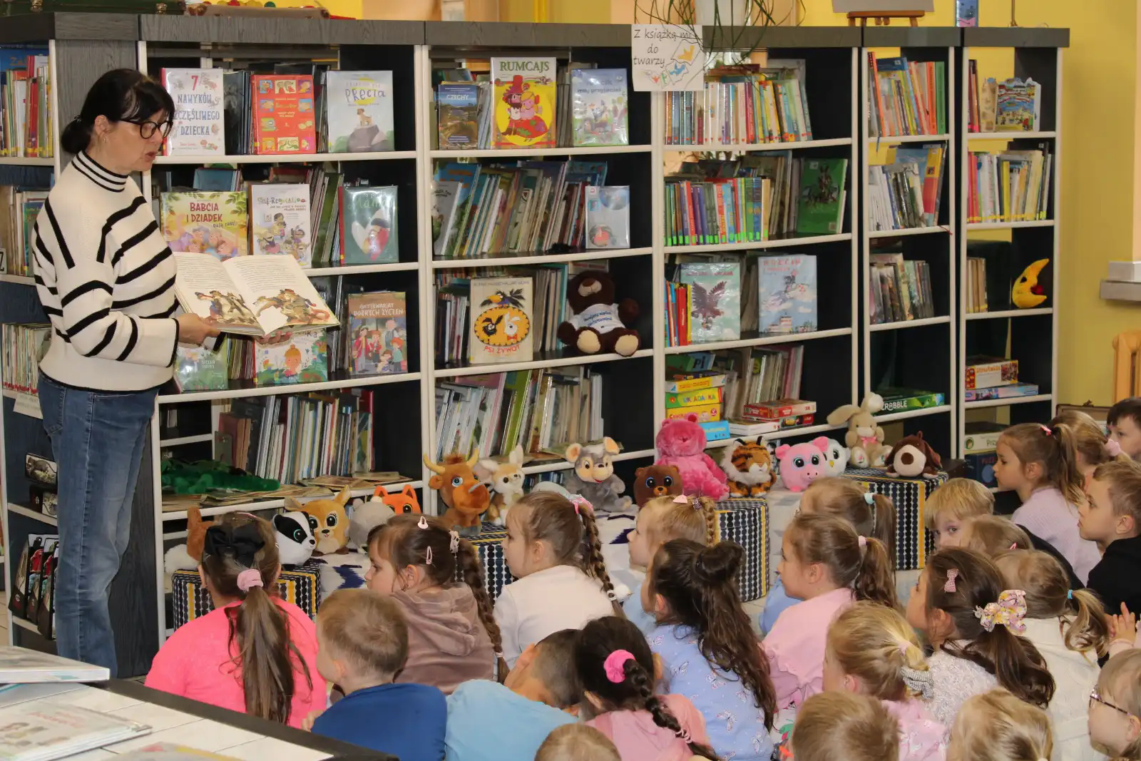 Pani bibliotekarka pokazuje dzieciom książki. 