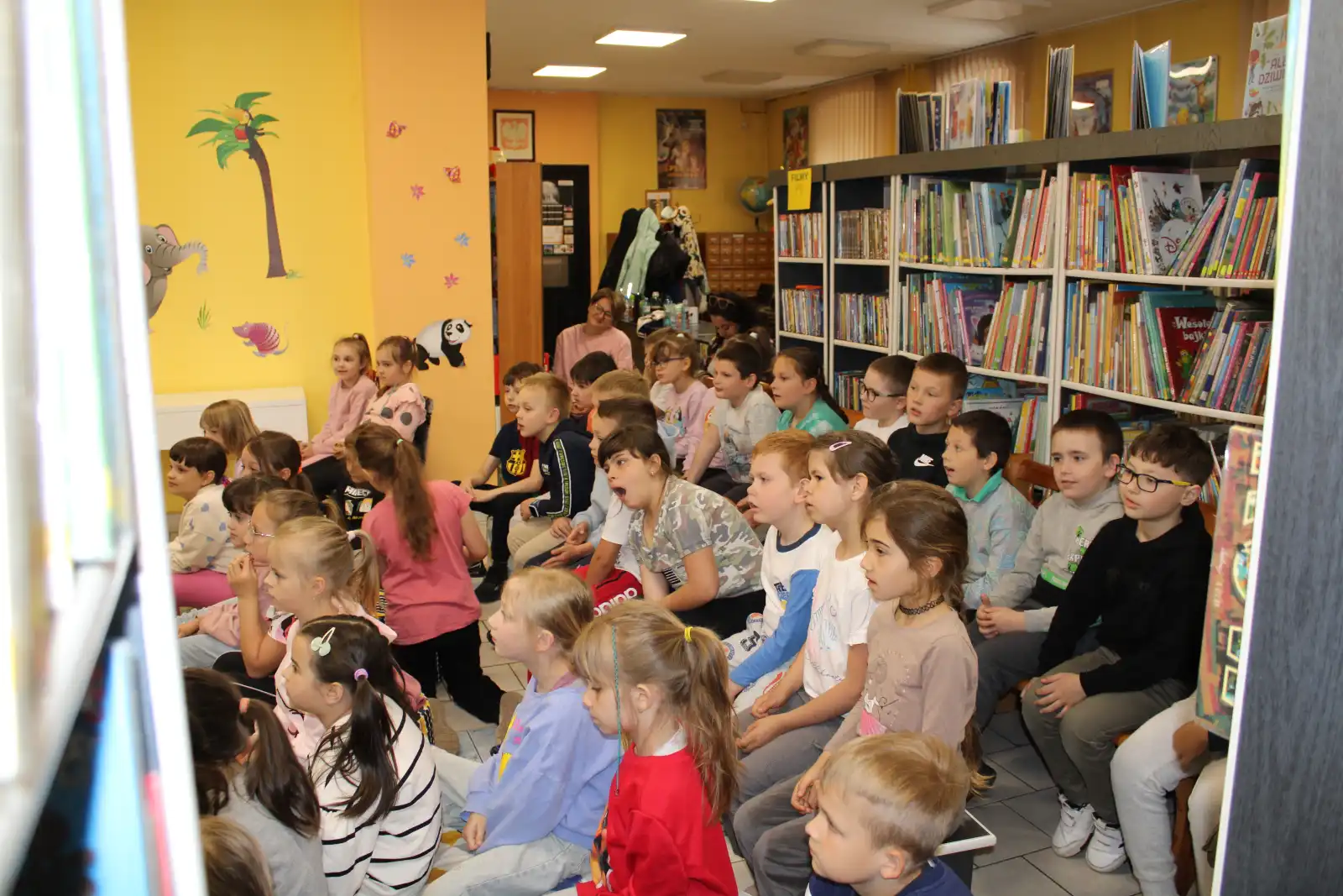 Dzieci siedzą na widowni i oglądają spektakl. 