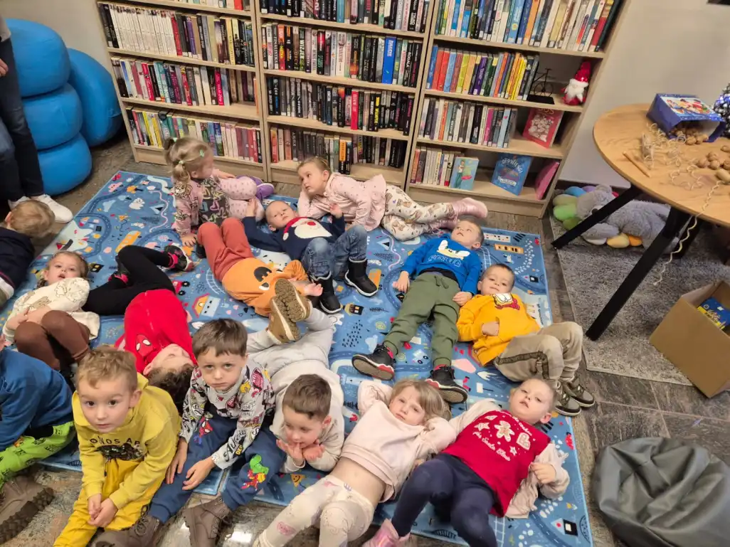 Grupa przedszkolaków leży na dywanie w Filii Nr 1.