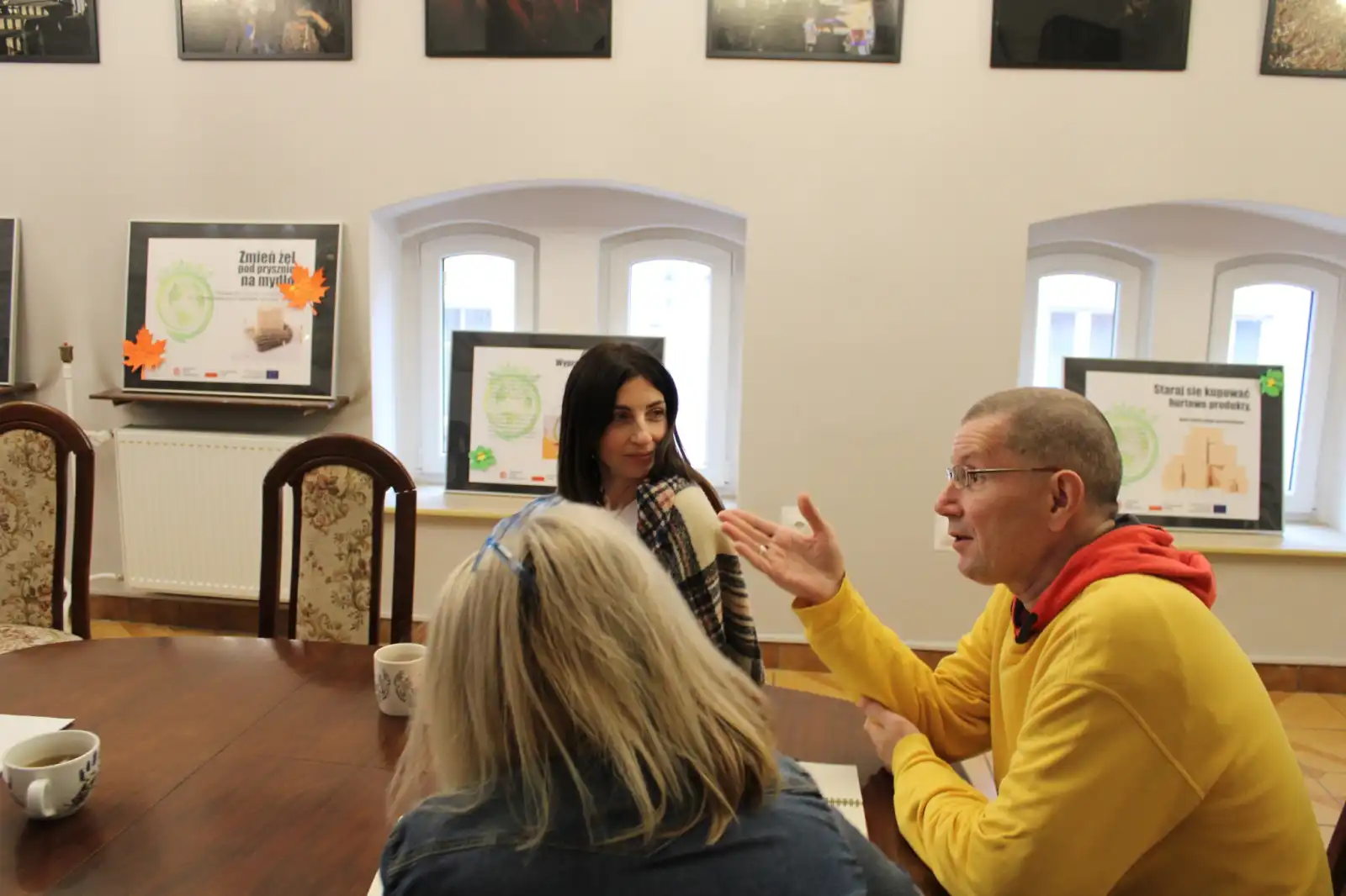 Pracownicy biblioteki siedzą przy stole w Sali kominkowej MBP.